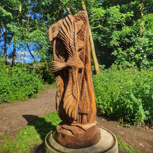 Wooden bird in front of woods