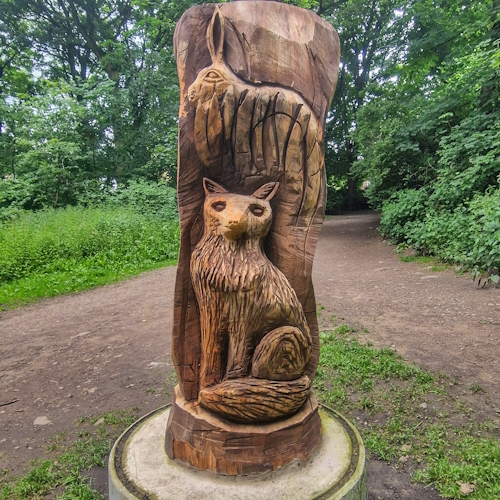 Wooden fox in front of a rabbit within woods