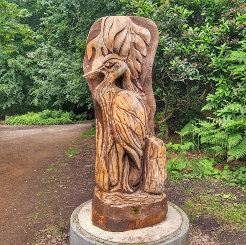 Wooden heron in leaves in woods