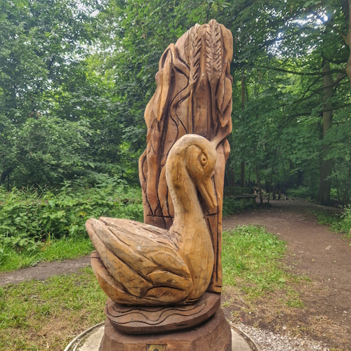 Wooden swan in reeds and water, in woods