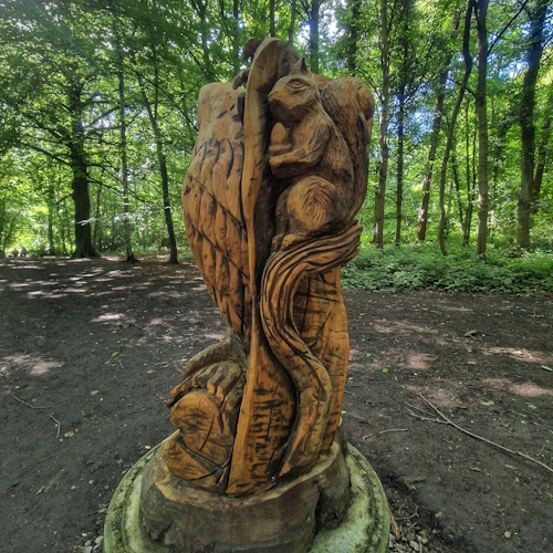 Wooden squirrel on a branch, in woods